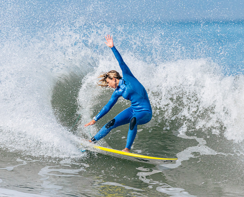 Sage surfing in a blue fullsuit wetsuit