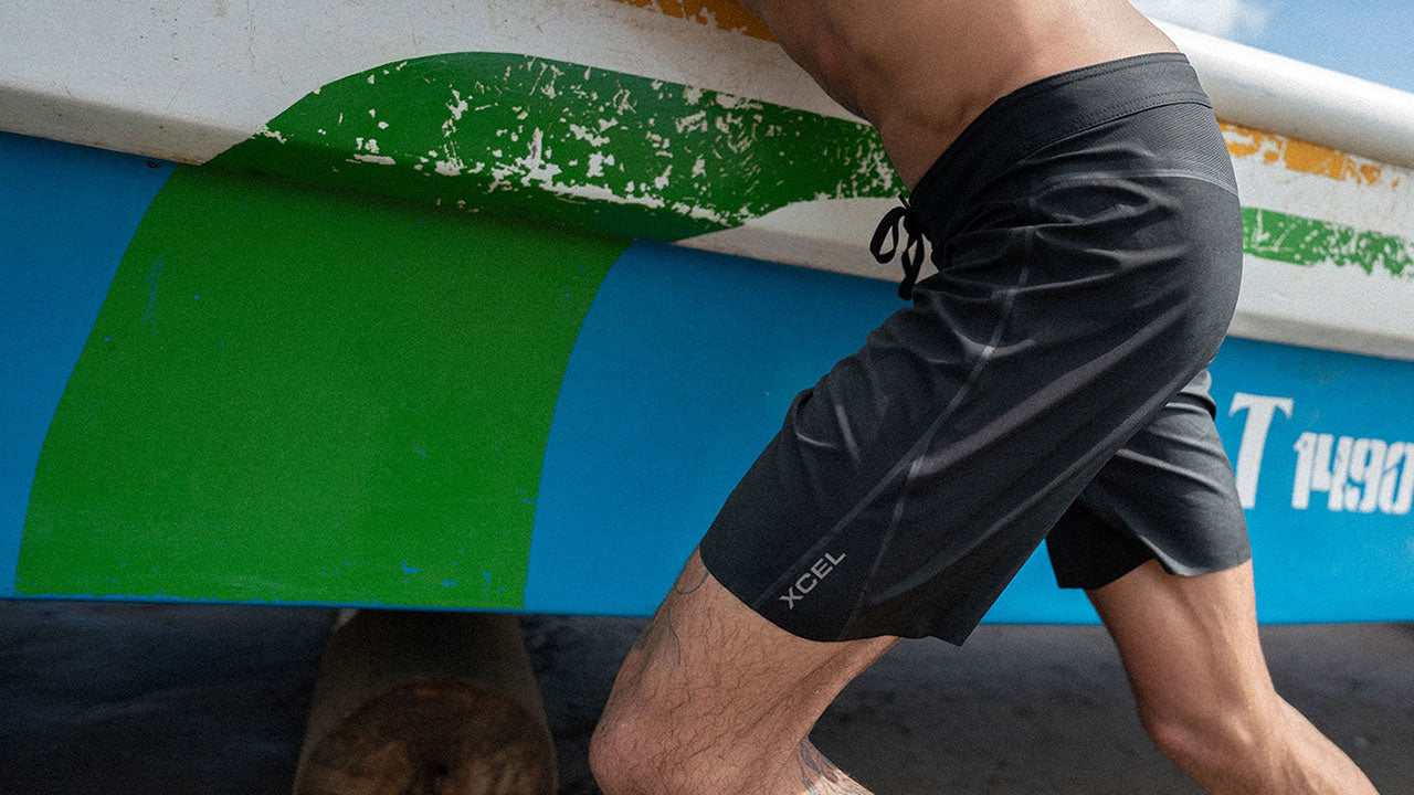Surfer carrying a boat in Xcel Drylock Boardshorts