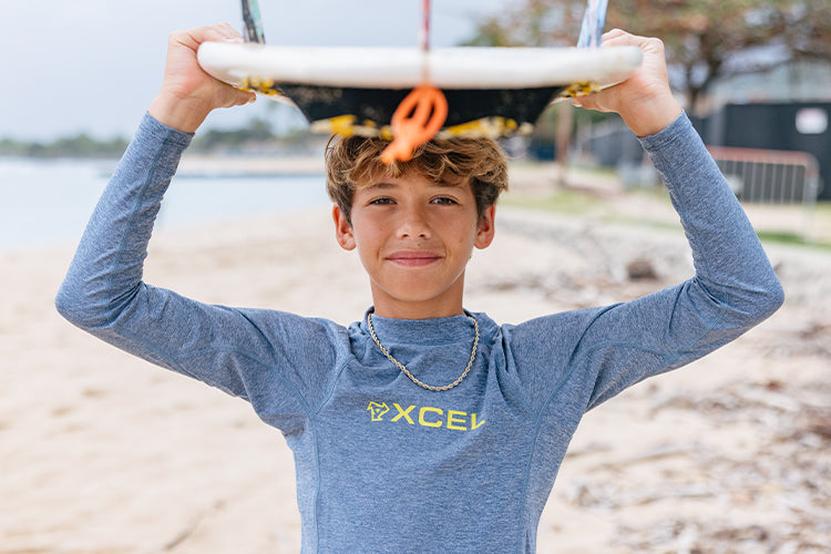 surfer in a rash guard holding surf board