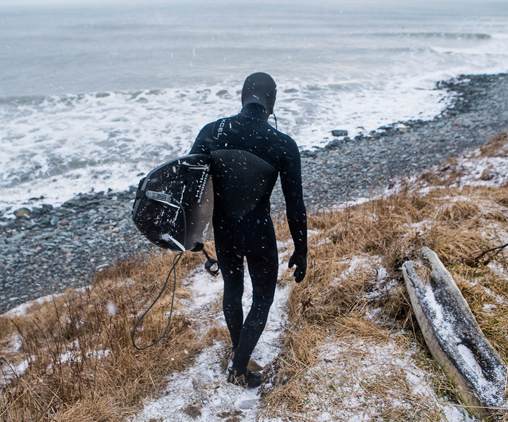surfer in wetsuit and boots on beach in cold weather