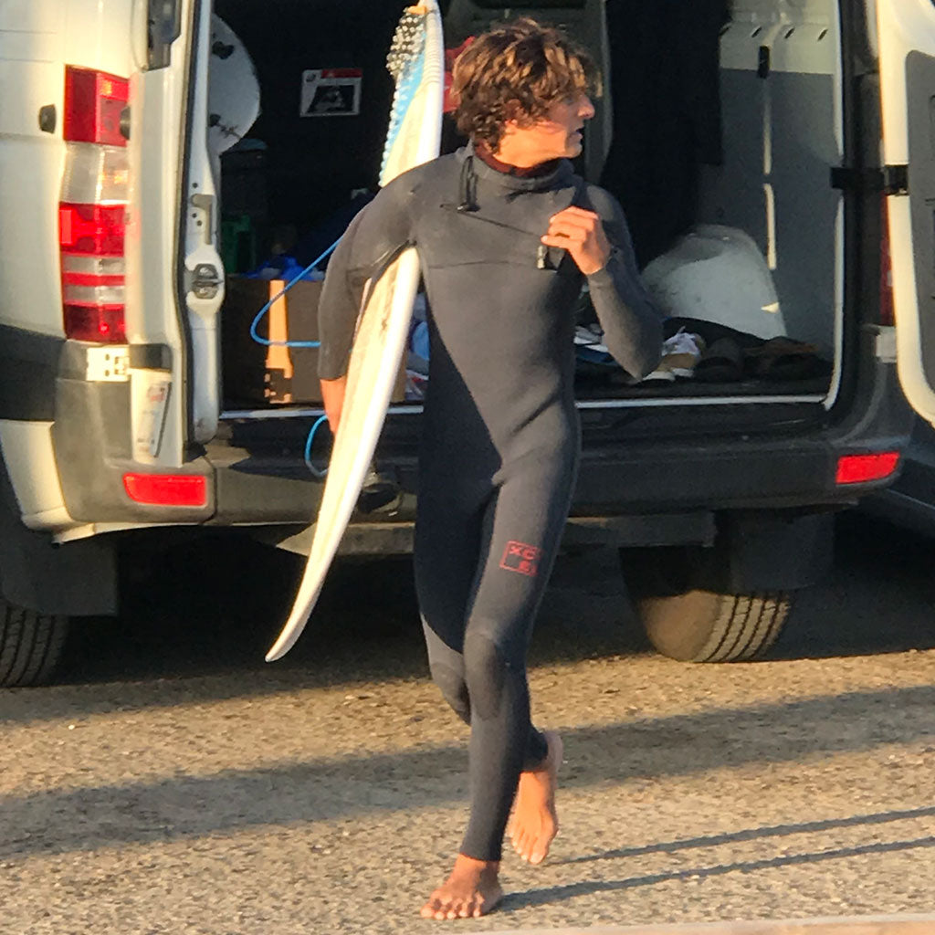 surfer exiting a van on beach