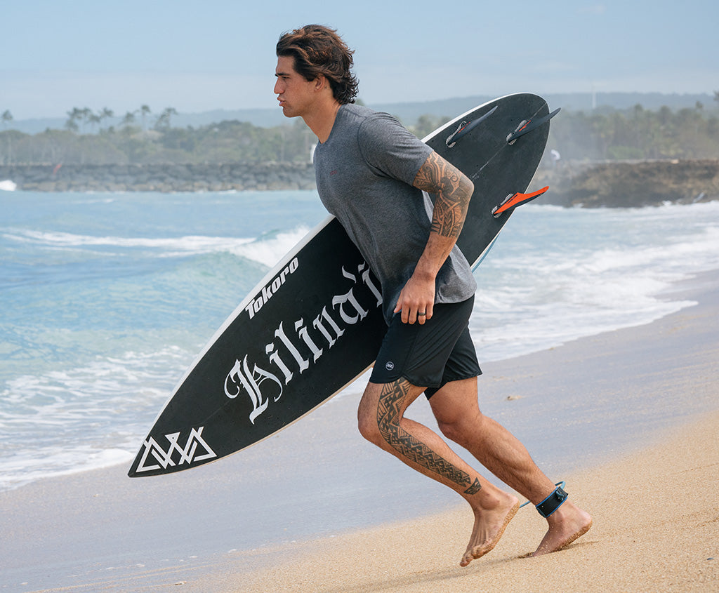 surfer on the beach with a surfboard in Xcel Thread X UV